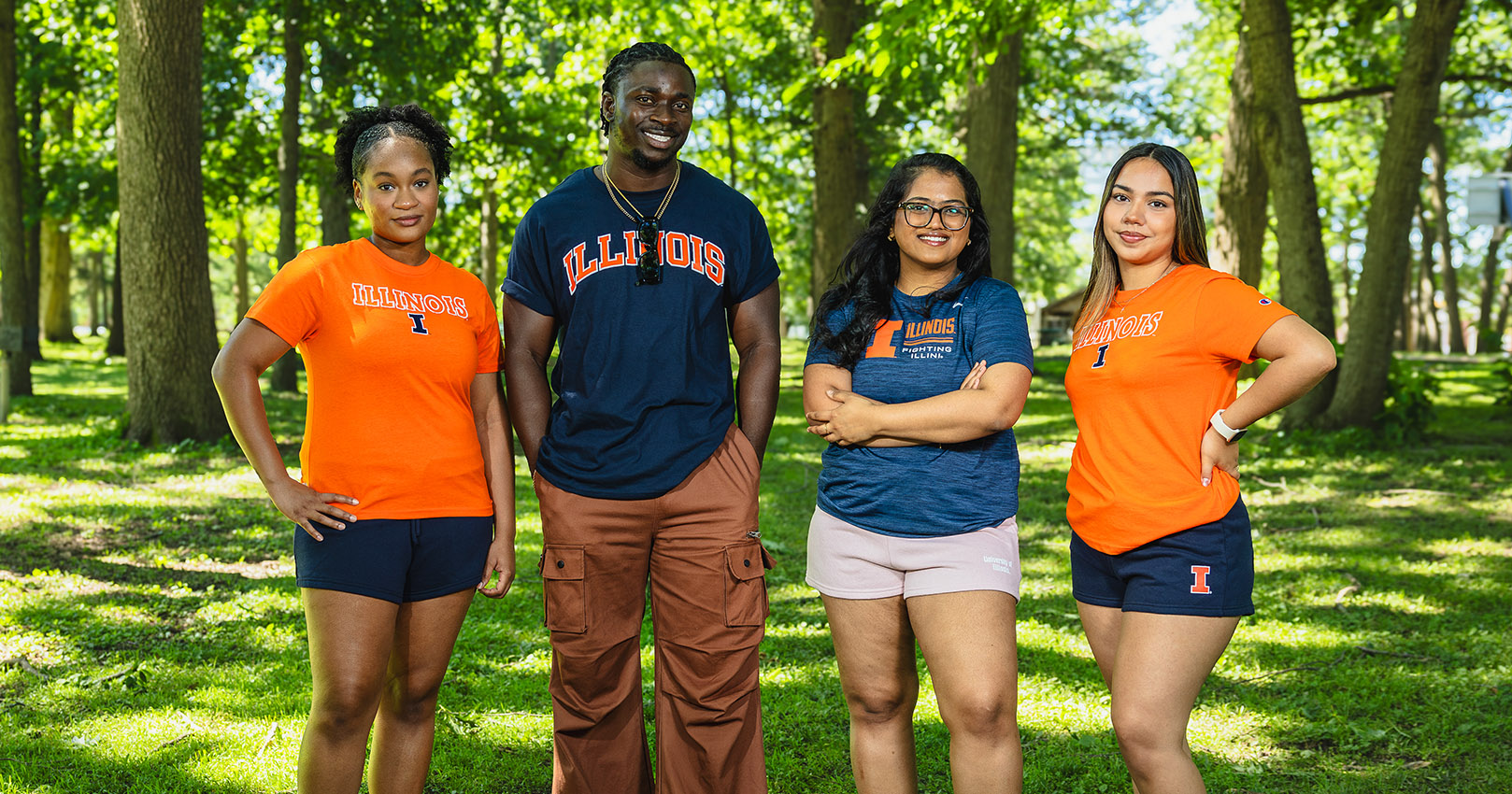 picture of 4 students wearing Illinois gear against standing in Illini Grove on campus